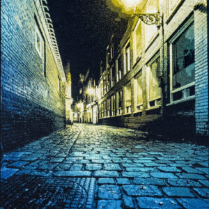 Logan Hicks stencil artwork of a quiet cobblestone street in Amsterdam at night lit by street lamps